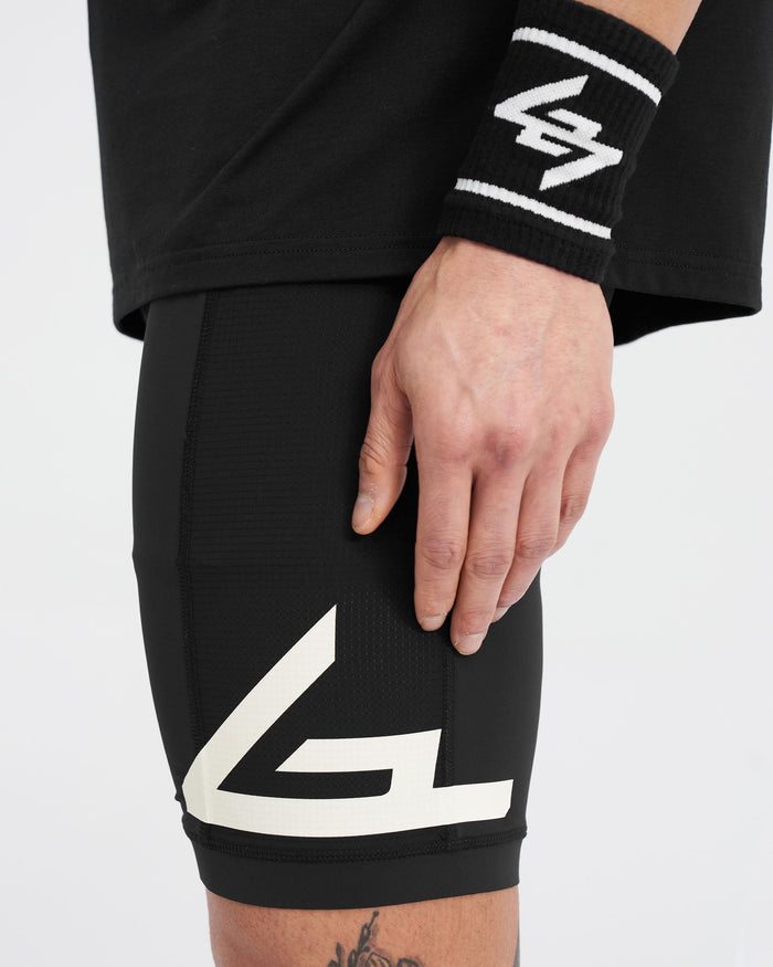 Man wearing black training shorts on a plain white background | 247 Cargo Half Tight in Jet Black | Stretch ripstop panelling and branded silicone leg grips | 247 Shorts | Represent Clo