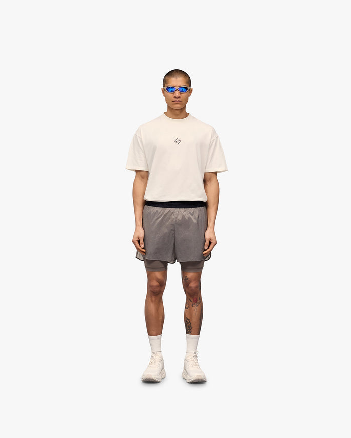 Man wearing beige shorts on a plain white background | 247 Contour 2-In-1 Run Shorts in Pebble | Shorts with inner legging and storage pockets | 247 Shorts | Represent Clo