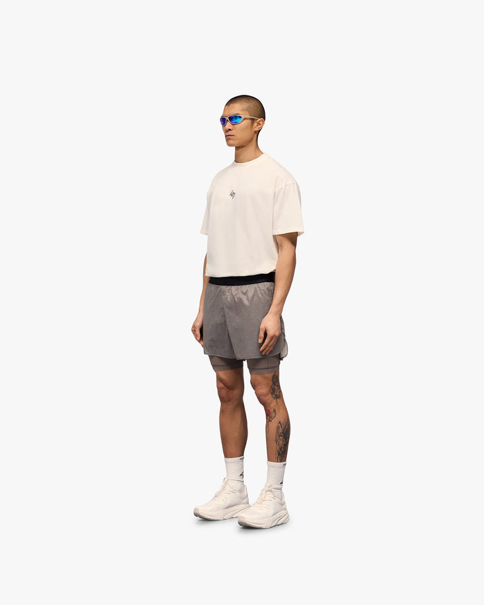 Man wearing grey 2-in-1 run shorts on a plain white background | 247 Contour 2-In-1 Run Shorts in Pebble | Shorts with inner legging and zip pockets | 247 Shorts | Represent Clo