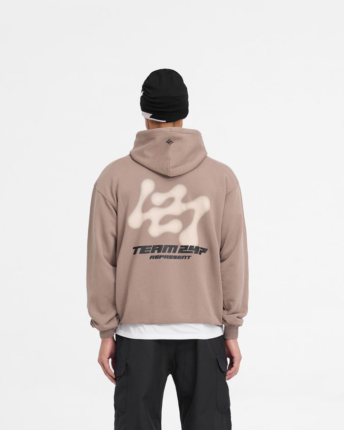 Man wearing an oversized brown hoodie on a plain white background | 247 Future Terrains Oversized Hoodie in Umber | Oversized hoodie with Team 247 branding | 247 Hoodies | Represent Clo