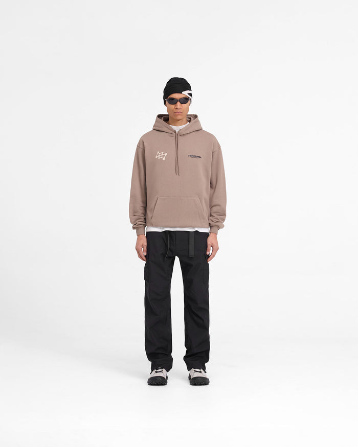 Man wearing an oversized brown hoodie on a plain white background | 247 Future Terrains Oversized Hoodie in Umber | Heavyweight cotton hoodie with Team 247 branding | 247 Hoodies | Represent Clo