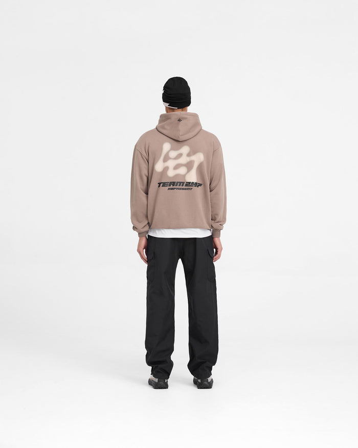 Man wearing an oversized umber hoodie on a plain white background | 247 Future Terrains Oversized Hoodie in Umber | Heavyweight cotton hoodie with Team 247 branding | 247 Hoodies | Represent Clo