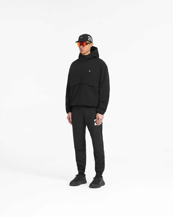 Man wearing a black hooded jacket on a plain white background | 247 Hooded Training Jacket in Jet Black | Nylon jacket with 4-way stretch and DWR coating | 247 Outerwear | Represent Clo