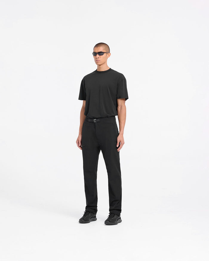 Man wearing black pants on a plain white background | 247 Mission Pant in Black | Stretch nylon straight leg pants with zip pockets | 247 Pants | Represent Clo