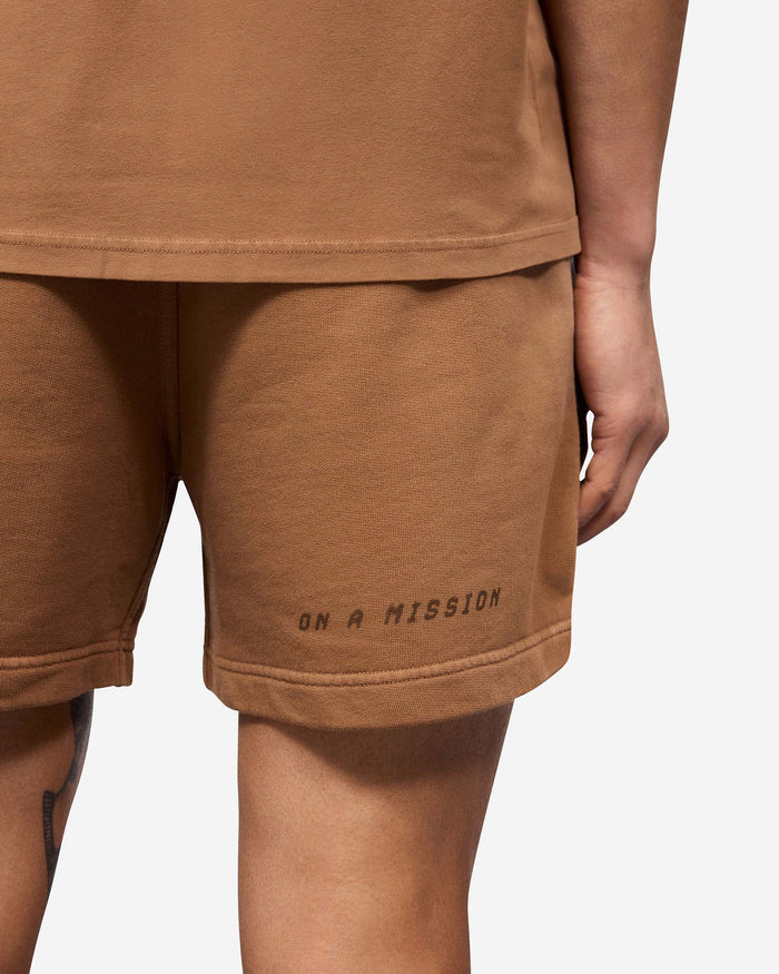 Man wearing rust jersey shorts on a plain white background | 247 Motion Shorts in Rust | Shorts with elasticated waistband and graphic print | 247 Shorts | Represent Clo