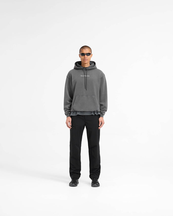 Man wearing a slightly oversized black hoodie on a plain white background | 247 On A Mission Hoodie in Aged Black | Heavy weight jersey cotton with ribbed trims | 247 Hoodies | Represent Clo