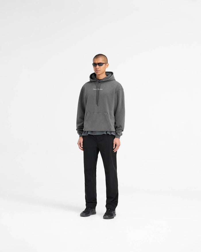 Man wearing an oversized black hoodie on a plain white background | 247 On A Mission Hoodie in Aged Black | Heavyweight jersey cotton hoodie with On A Mission and 247 embroidery | 247 Hoodies | Represent Clo
