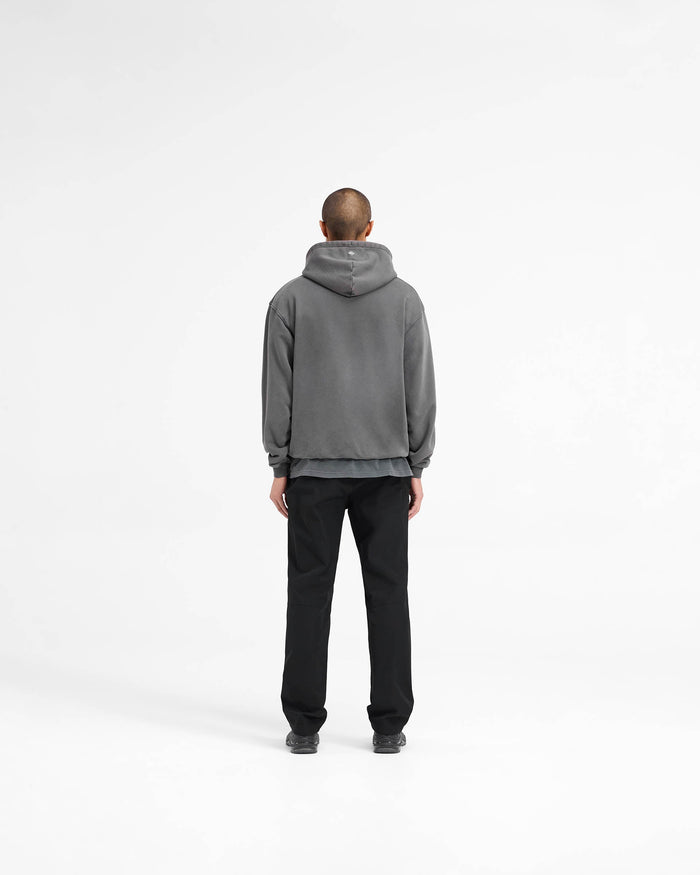 Man wearing a black hoodie on a plain white background | 247 On A Mission Hoodie in Aged Black | Oversized hoodie with embroidery and ribbed trims | 247 Hoodies | Represent Clo