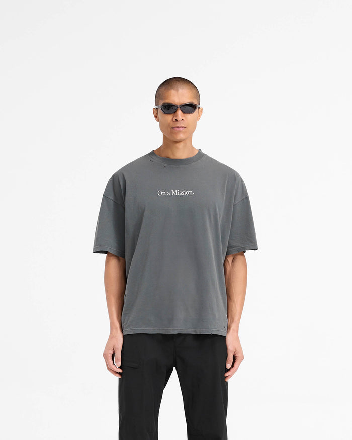 Man wearing an oversized black t-shirt on a plain white background | 247 On A Mission Oversized T-Shirt in Aged Black | T-Shirt with On a Mission embroidery and distressing details | 247 T-Shirts | Represent Clo