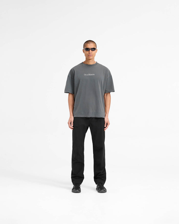 Man wearing a black oversized t-shirt on a plain white background | 247 On A Mission Oversized T-Shirt in Aged Black | Lightweight jersey cotton with embroidery | 247 T-Shirts | Represent Clo