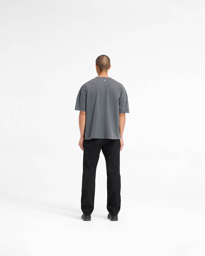 Man wearing a black oversized t-shirt on a plain white background | 247 On A Mission Oversized T-Shirt in Aged Black | Slightly oversized t-shirt with distressing details and embroidery | 247 T-Shirts | Represent Clo