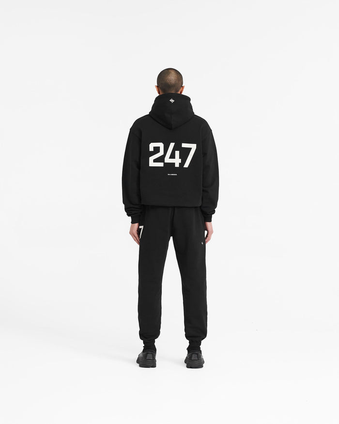 Man wearing an oversized black hoodie on a plain white background | 247 Oversized Hoodie in Jet Black | Oversized fit hoodie with ribbed cuffs and hem | 247 Hoodies | Represent Clo