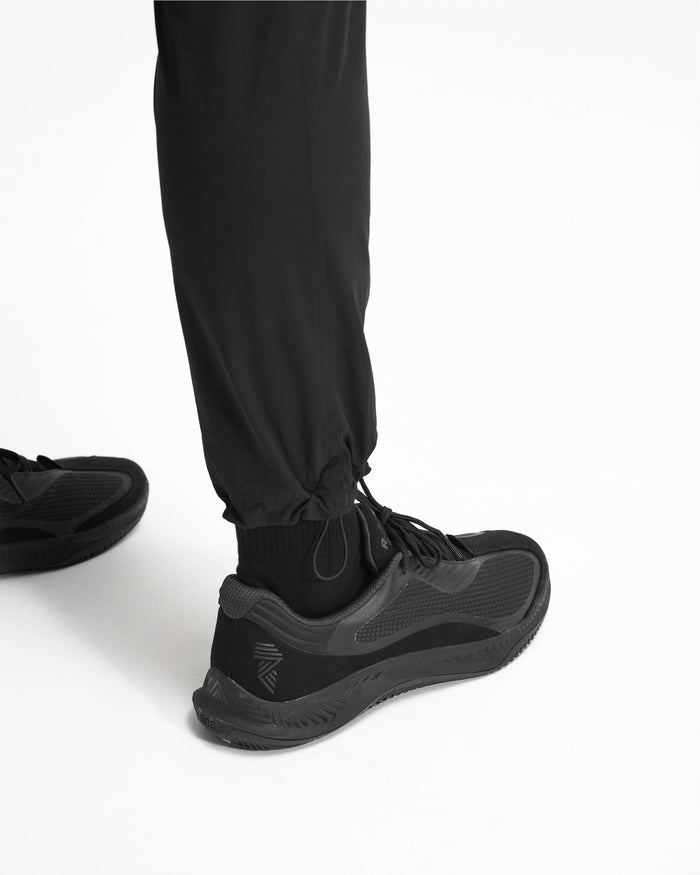 Man wearing black cargo pants on a plain white background | 247 Pant in Black | Versatile cargo pants with 4-way stretch and zip pockets | 247 Pants | Represent Clo