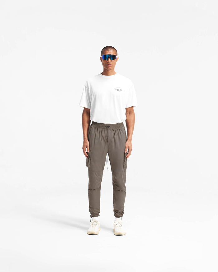 Man wearing olive cargo pants on a plain white background | 247 Pant in Olive | Lightweight pants with cargo pockets and adjustable hem | 247 Pants | Represent Clo