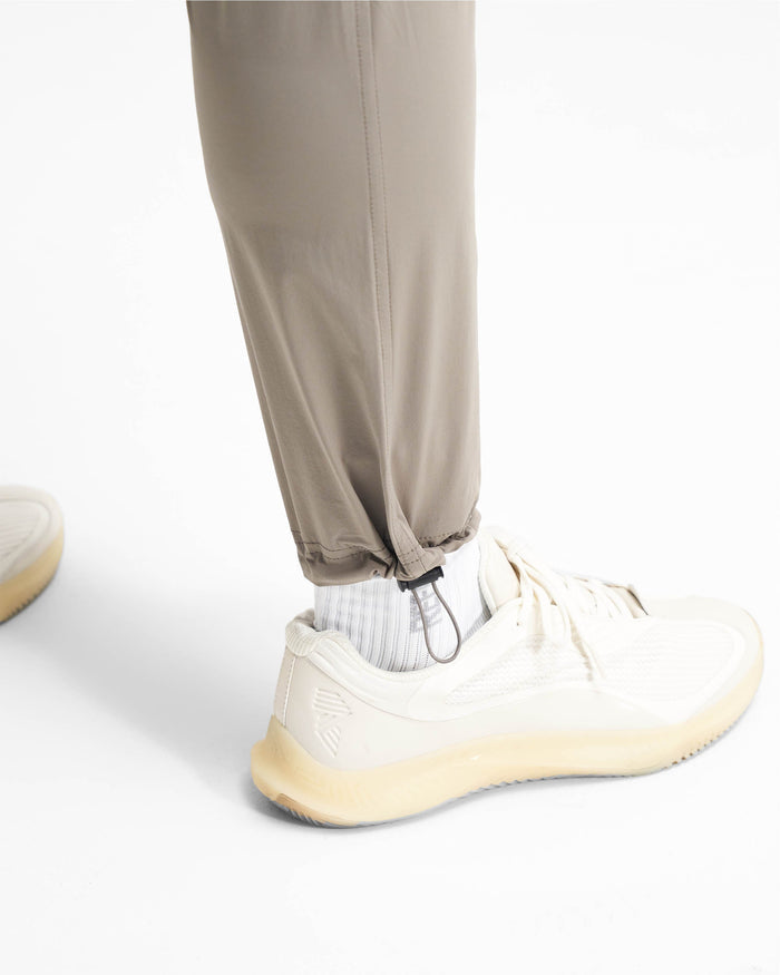 Man wearing taupe cargo pants on a plain white background | 247 Pant in Taupe | Cargo pants with 4-way stretch and zip pockets | 247 Pants | Represent Clo