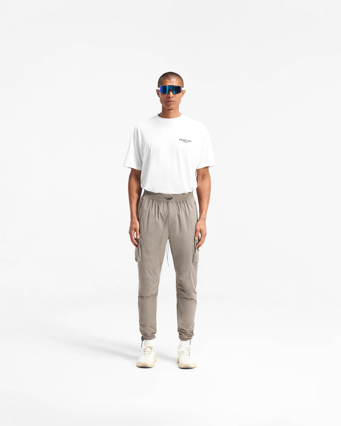 Man wearing taupe pants on a plain white background | 247 Pant in Taupe | Versatile cargo silhouette with adjustable bungee cord hem | 247 Pants | Represent Clo