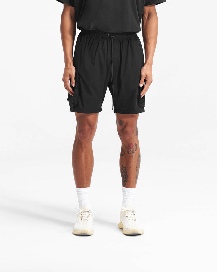 Man wearing black cargo shorts on a plain white background | 247 Shorts in Black | Mens combat shorts with elasticated drawstring waist | 247 Shorts | Represent Clo