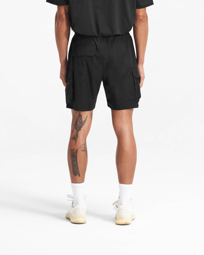 Man wearing black shorts on a plain white background | 247 Shorts in Black | Combat shorts with cargo leg pockets and zip side pockets | 247 Shorts | Represent Clo