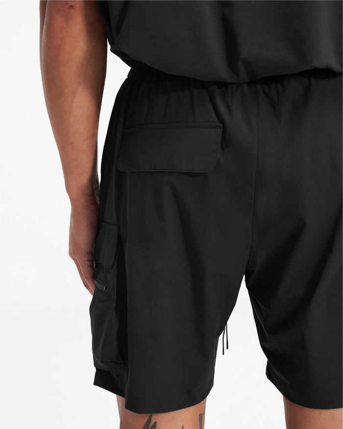 Man wearing black combat shorts on a plain white background | 247 Shorts in Black | Combat shorts with cargo pockets and elasticated drawstring waist | 247 Shorts | Represent Clo