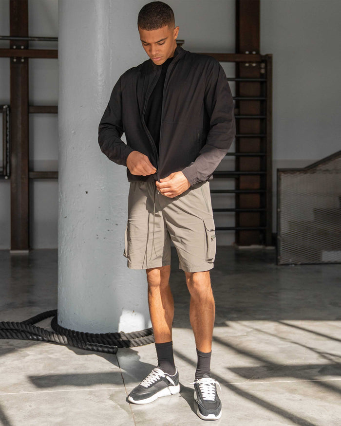 Man wearing olive shorts on a plain white background | 247 Shorts in Olive | Mens combat shorts with cargo leg pockets | 247 Shorts | Represent Clo