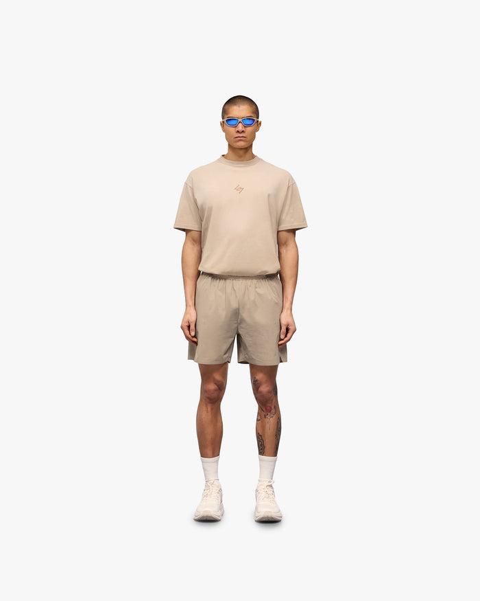 Man wearing grey training shorts on a plain white background | 247 Training Shorts in Pebble | Nylon and spandex shorts with perforation detailing | 247 Shorts | Represent Clo