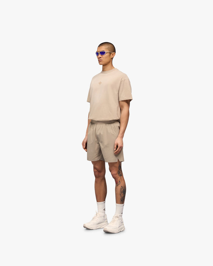 Man wearing grey training shorts with perforation detailing on a plain white background | 247 Training Shorts in Pebble | Flexible nylon and spandex shorts with zip pockets | 247 Shorts | Represent Clo