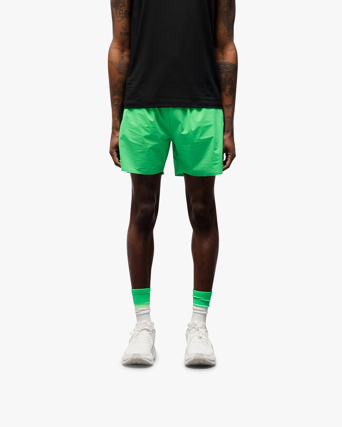 Man wearing green training shorts on a plain white background | 247 Training Shorts in Speed Green | Shorts with perforation detailing and zip pockets | 247 Shorts | Represent Clo