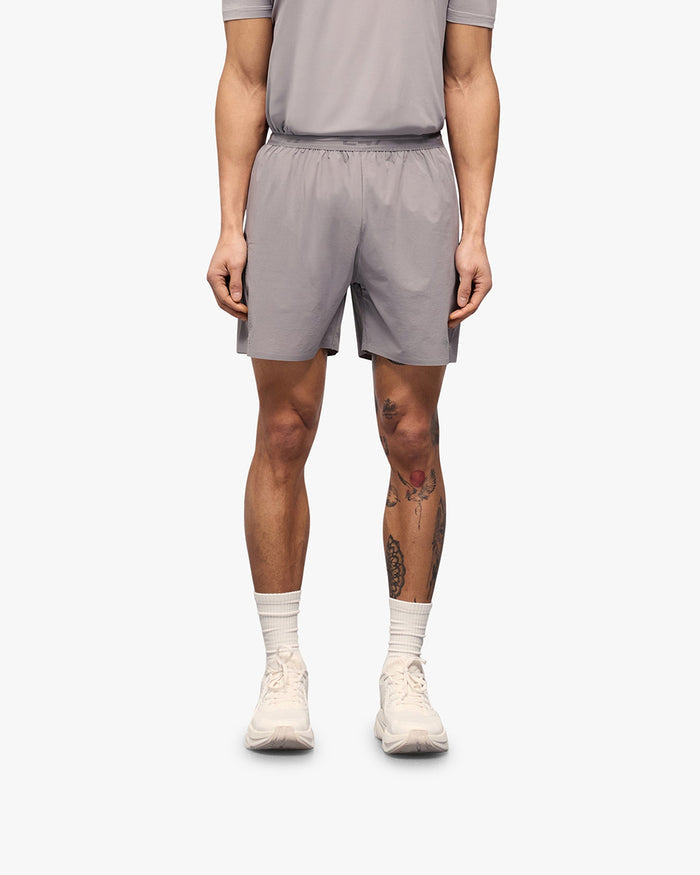 Man wearing grey training shorts on a plain white background | 247 Training Shorts in Titanium | Nylon blend shorts with perforation detailing | 247 Shorts | Represent Clo