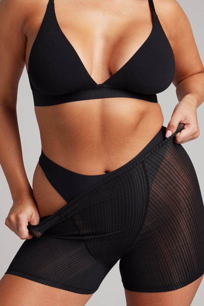Black high-rise thong with wide waistband, worn by model
