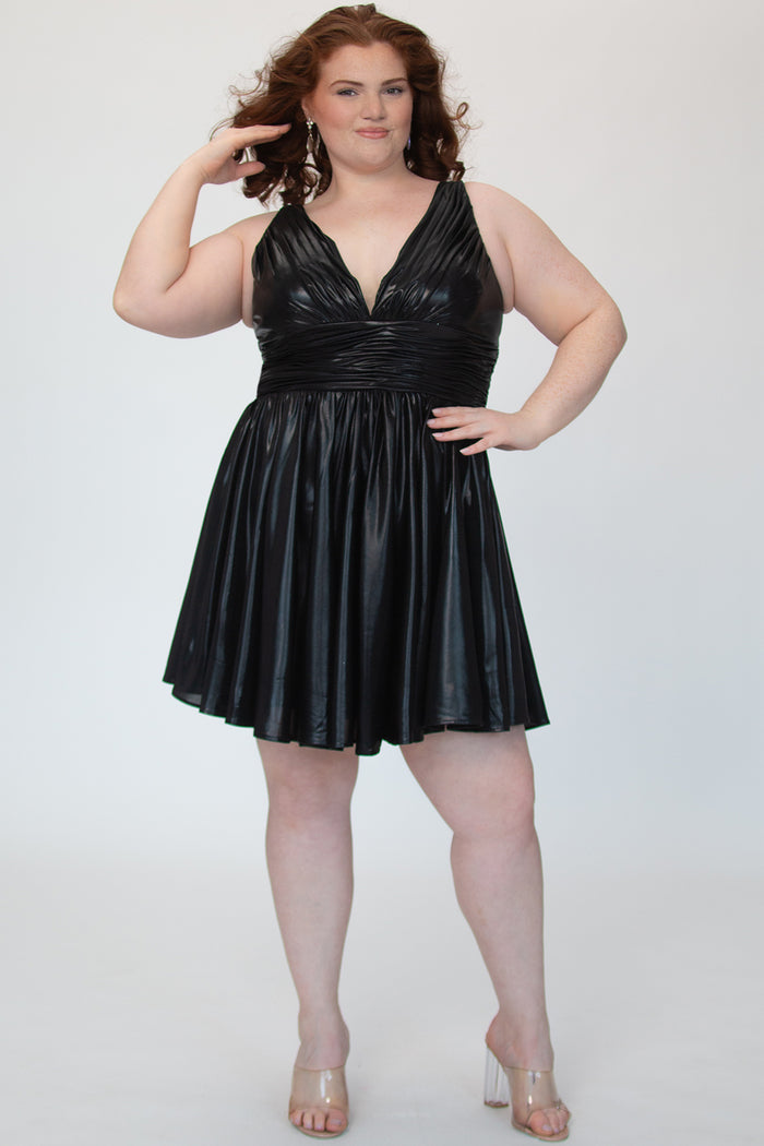 A-line flowy short party dress, SC8156 by Sydney's Closet. Front view. In the color raven black, a  metallic knit fabric. Thick bra-friendly straps, pleated v-neckline bodice and waist band, long invisible center back zipper. V- back. Available in Prism, Peacock and Raven black, sizes 14-32. 
Model in picture is 5'9.