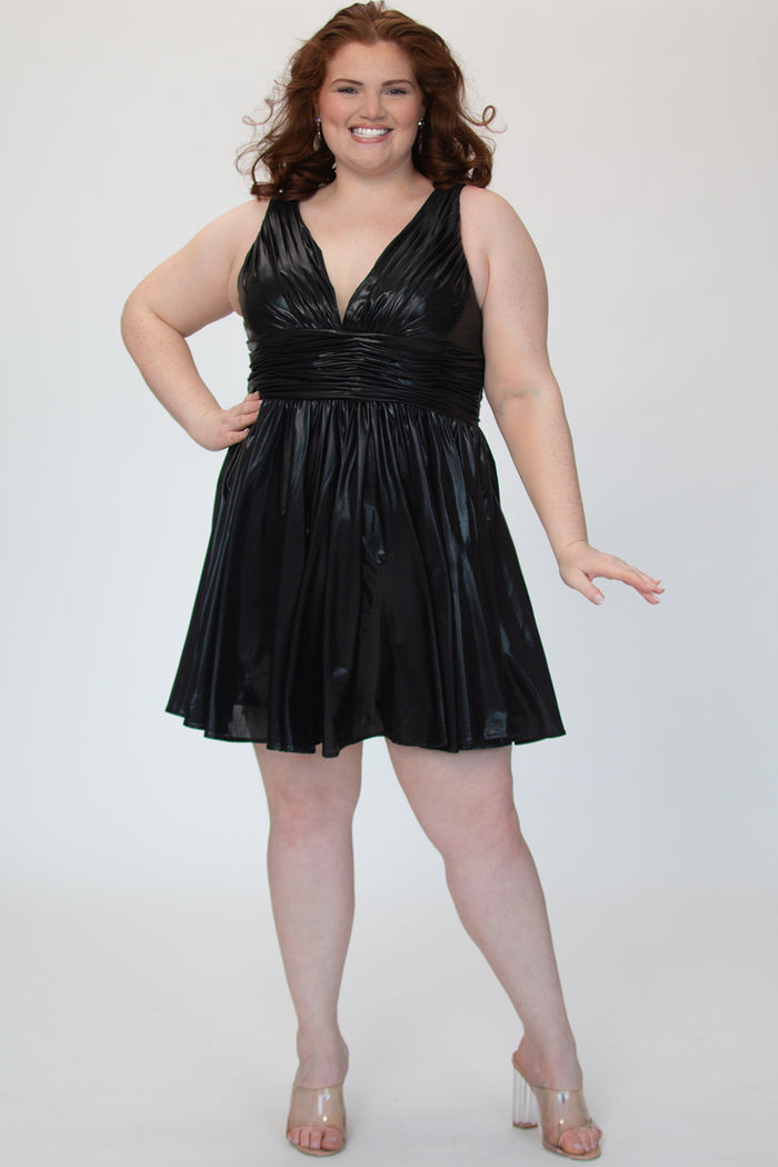 A-line flowy short party dress, SC8156 by Sydney's Closet. Front view. In the color raven black, a  metallic knit fabric. Thick bra-friendly straps, pleated v-neckline bodice and waist band, long invisible center back zipper. V- back. Available in Prism, Peacock and Raven black, sizes 14-32. 
Model in picture is 5'9.