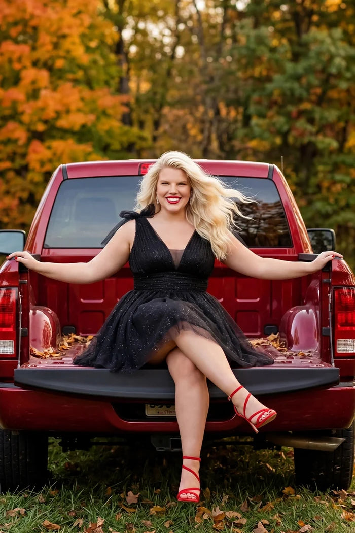 Woman in a black dress sitting on the back of a red pickup truck with autumn foliage in the background

Short A-line plus size flowy party dress SC8153 by Sydney's Closet in the color Onyx black. Front view. Layers of dense sparkle tulle and a satin lining. V-neckline with thick bra-friendly straps and detachable bows at the top of the shoulder. Pleated bodice and 3 inch pleated waistband. Pockets and long invisible center back zipper. Available in Shamrock green, Admiral blue, Firecracker red and Shamrock