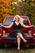 Woman in a black dress sitting on the back of a red pickup truck with autumn foliage in the background

Short A-line plus size flowy party dress SC8153 by Sydney's Closet in the color Onyx black. Front view. Layers of dense sparkle tulle and a satin lining. V-neckline with thick bra-friendly straps and detachable bows at the top of the shoulder. Pleated bodice and 3 inch pleated waistband. Pockets and long invisible center back zipper. Available in Shamrock green, Admiral blue, Firecracker red and Shamrock