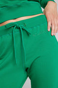 Green jogger pants close-up with drawstring waist and 'NEGATIVE' pocket text