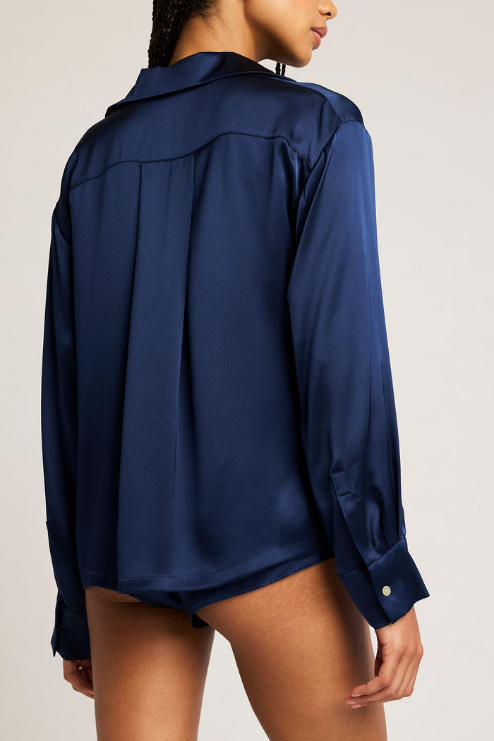 Back view of navy button-up shirt with long sleeves and yoke pleat