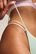 Pastel green string thong with mixed-color waist and side straps.