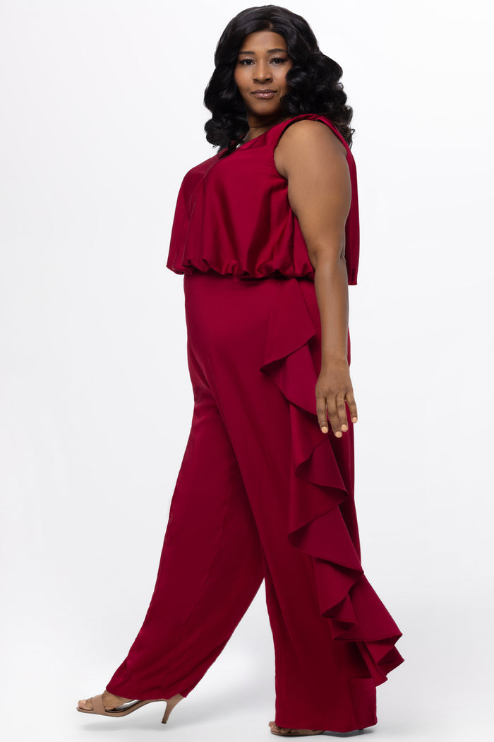 Celebrations by Sydney's Closet Style CE2615 in cherry red.

One-piece crepe satin jumpsuit with ruffled on outer pants seams. Bra-friendly straps, blouson bodice and wide leg pants. Center back zipper and scoop neckline.