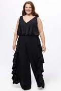 Celebrations by Sydney's Closet Style CE2615 in Black.

One-piece crepe satin jumpsuit with ruffled on outer pants seams. Bra-friendly straps, blouson bodice and wide leg pants. Center back zipper and scoop neckline.