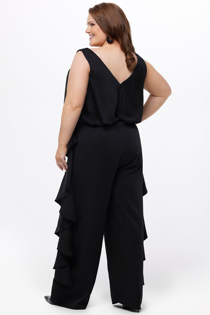 Celebrations by Sydney's Closet Style CE2615 in Black.

One-piece crepe satin jumpsuit with ruffled on outer pants seams. Bra-friendly straps, blouson bodice and wide leg pants. Center back zipper and scoop neckline.