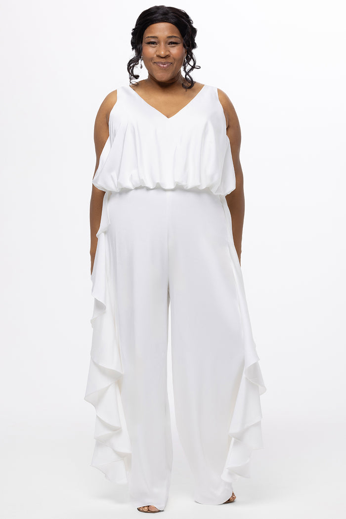 Celebration's by Sydney's Closet style CE2615 in Ivory. 

Crepe satin jumpsuit with a V-neck, bra-friendly straps, wide leg pants and blouson bodice. Ruffle detail on outer seams of pants. V-back with long center back zipper.