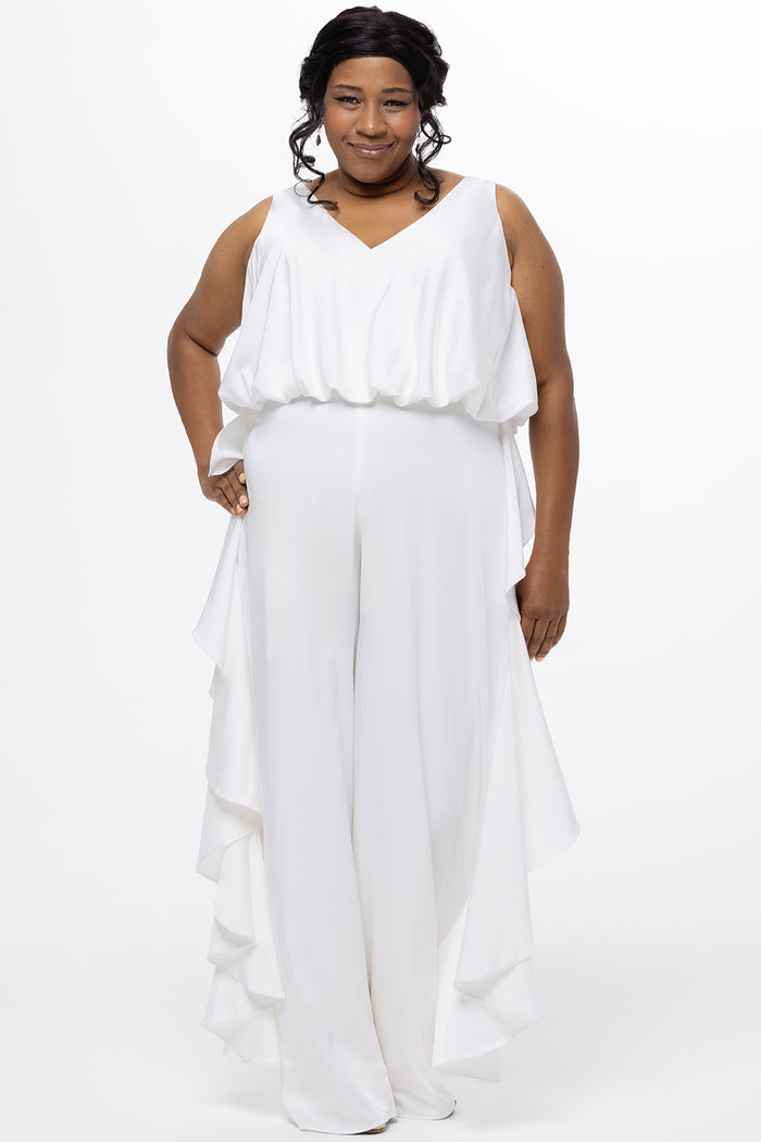 Celebration's by Sydney's Closet style CE2615 in Ivory. 

Crepe satin jumpsuit with a V-neck, bra-friendly straps, wide leg pants and blouson bodice. Ruffle detail on outer seams of pants. V-back with long center back zipper.