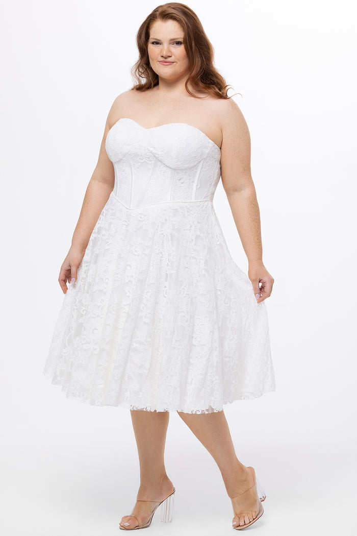 Celebrations by Sydney's Closet Style CE2613 in white. 

Plus size strapless white tea-length dress with sweetheart neckline, exposed corset boning on bustier bodice and tea-length skirt in all over stretch lace.