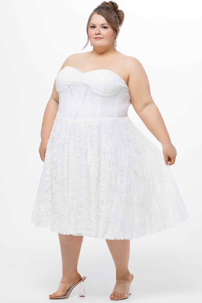Celebrations by Sydney's Closet Style CE2613 in white. 

Plus size strapless white tea-length dress with sweetheart neckline, exposed corset boning on bustier bodice and tea-length skirt in all over stretch lace.