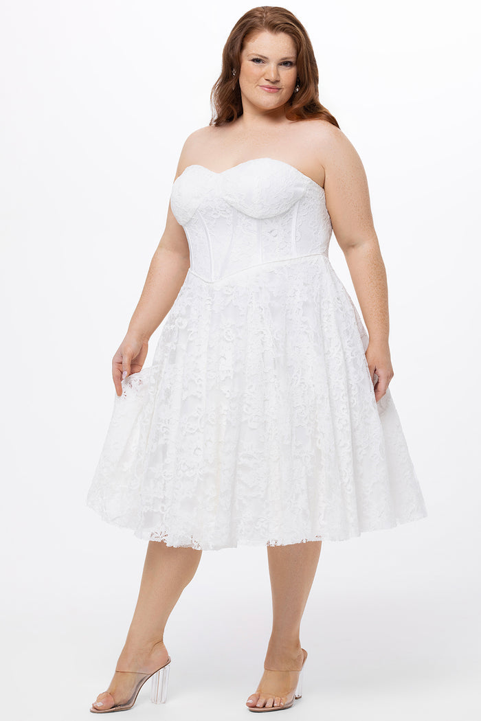 Celebrations by Sydney's Closet Style CE2613 in white. 

Plus size strapless white tea-length dress with sweetheart neckline, exposed corset boning on bustier bodice and tea-length skirt in all over stretch lace.