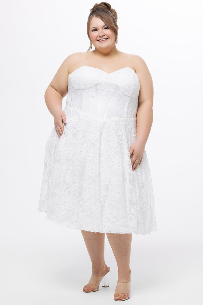 Celebrations by Sydney's Closet Style CE2613 in white. 

Plus size strapless white tea-length dress with sweetheart neckline, exposed corset boning on bustier bodice and tea-length skirt in all over stretch lace.