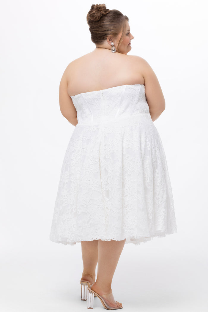 Celebrations by Sydney's Closet Style CE2613 in white. 

Plus size strapless white tea-length dress with sweetheart neckline, exposed corset boning on bustier bodice and tea-length skirt in all over stretch lace.