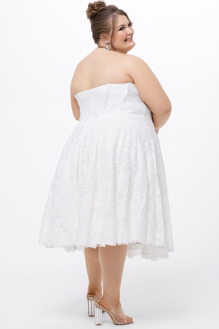 Celebrations by Sydney's Closet Style CE2613 in white. 

Plus size strapless white tea-length dress with sweetheart neckline, exposed corset boning on bustier bodice and tea-length skirt in all over stretch lace.