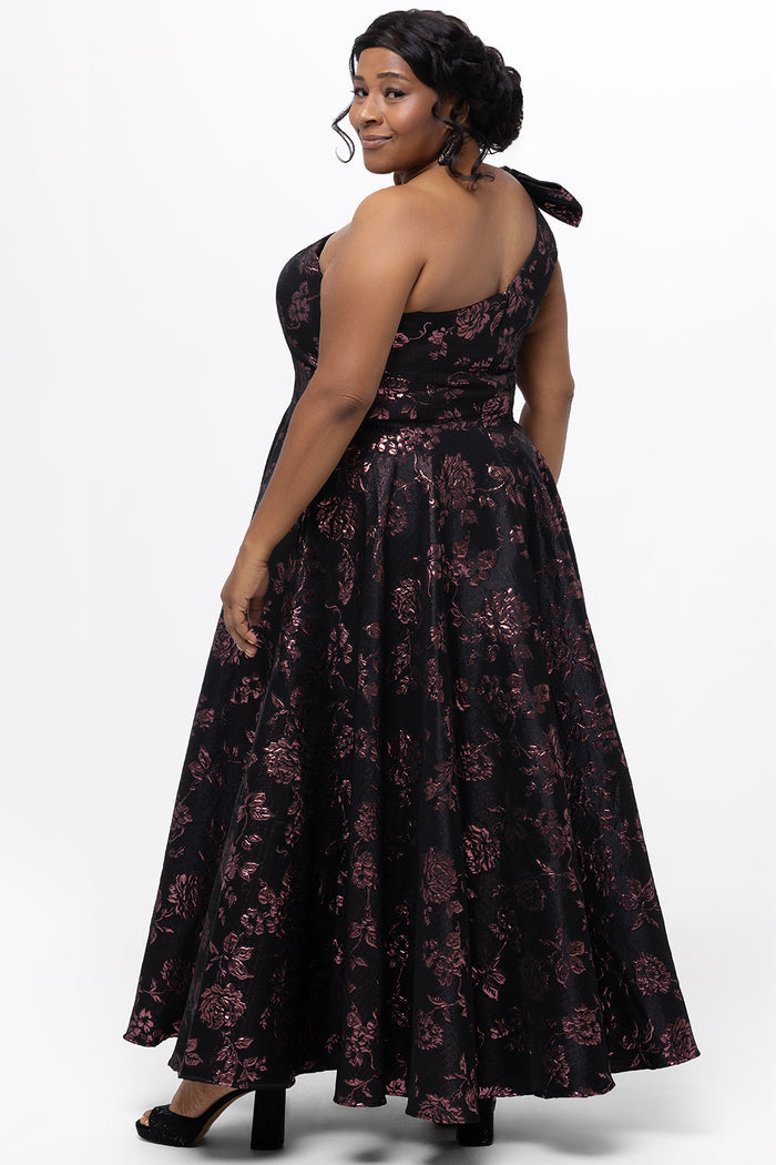 Celebrations by Sydney's Closet Style CE2614 in Pink Rose and Black floral brocade fabric.

Plus size maxi length formal dress. One-shoulder neckline with detachable bow at high point of shoulder, natural waistline and A-line skirt with pockets.