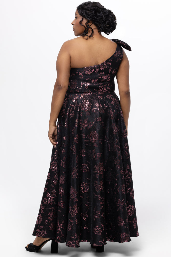 Celebrations by Sydney's Closet Style CE2614 in Pink Rose and Black floral brocade fabric.

Plus size maxi length formal dress. One-shoulder neckline with detachable bow at high point of shoulder, natural waistline and A-line skirt with pockets.