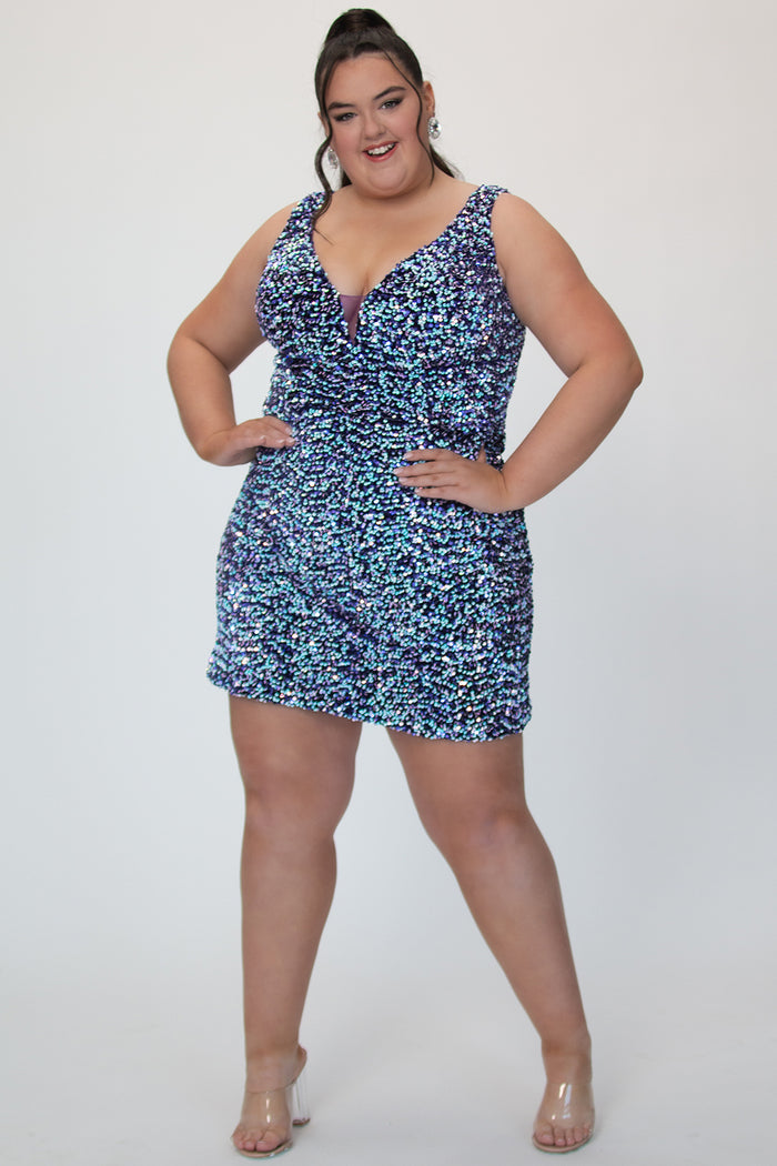 SC8158, plus size short sequin party dress by Sydney's Closet. Front view. A fully multidimensional sequin fabric in the color Galaxy, a mixture of blues and purples. V-neckline, thick bra-friendly straps, ruched skirt and long invisible center back zipper. Available in Galaxy, sizes 14-24. Model is 5'9.